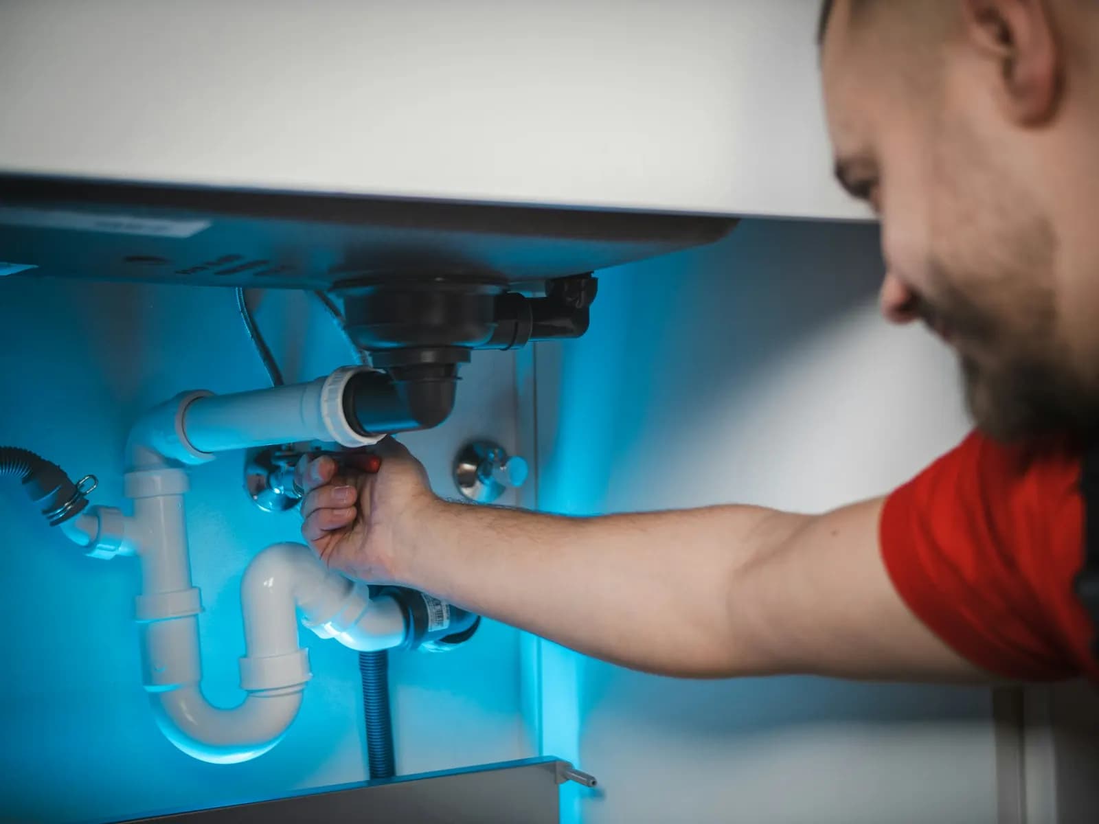 Plumber working on the waste pipe under a sink